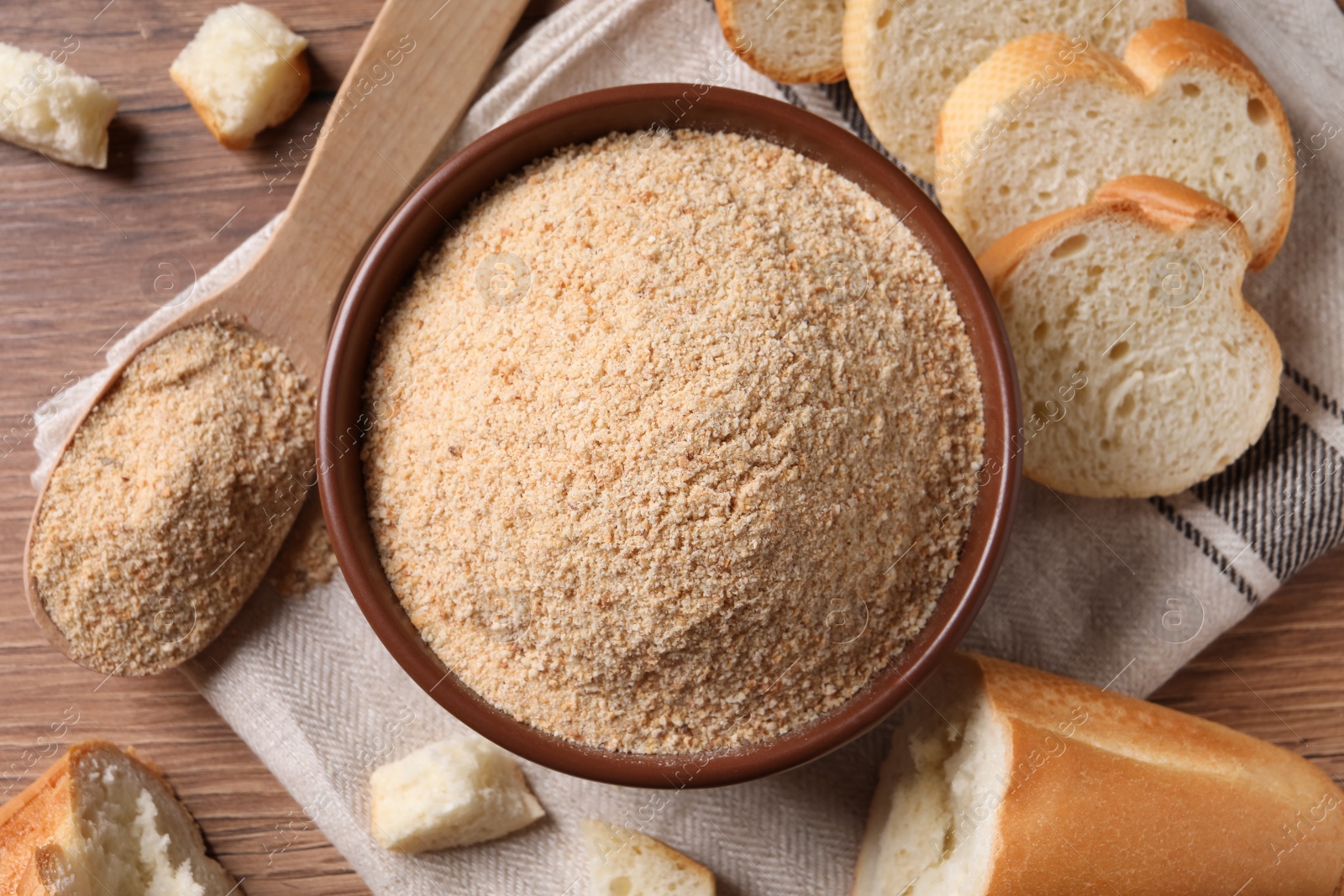 Photo of Fresh bread crumbs in bowl on wooden table, flat lay