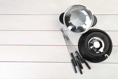 Fondue set on white wooden table, flat lay. Space for text