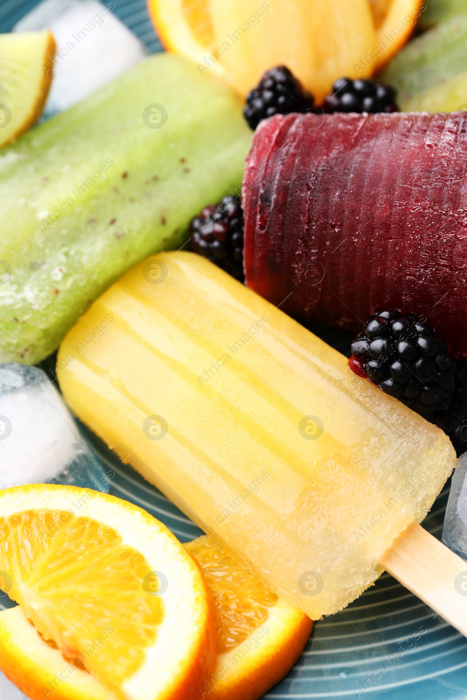 Photo of Delicious popsicle, ice cubes and fresh fruits on plate, closeup