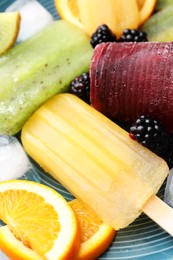 Photo of Delicious popsicle, ice cubes and fresh fruits on plate, closeup