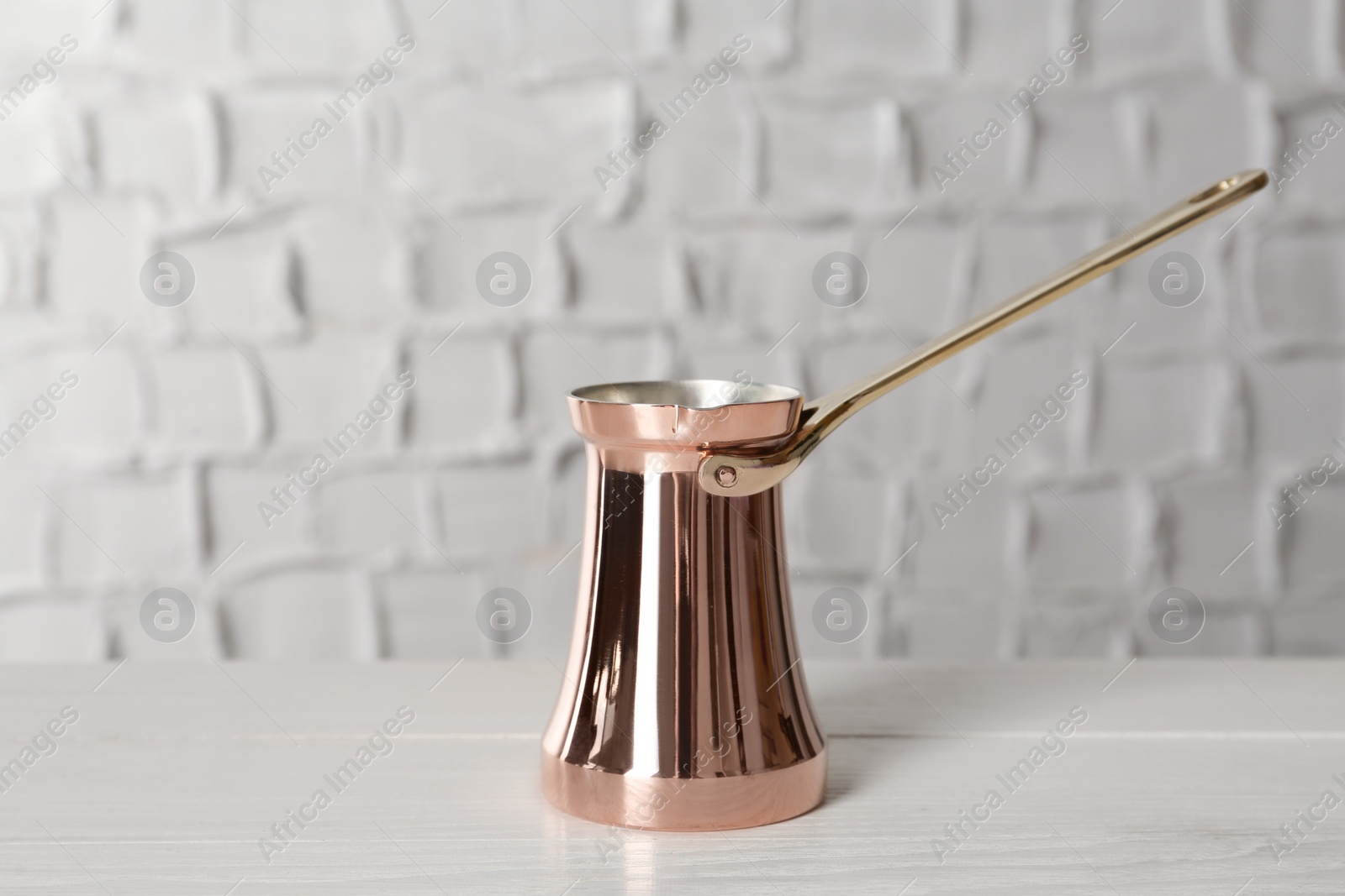 Photo of Copper turkish coffee pot on white wooden table