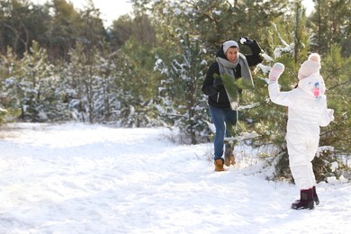 Father and daughter having snowball fight outdoors on winter day. Christmas vacation