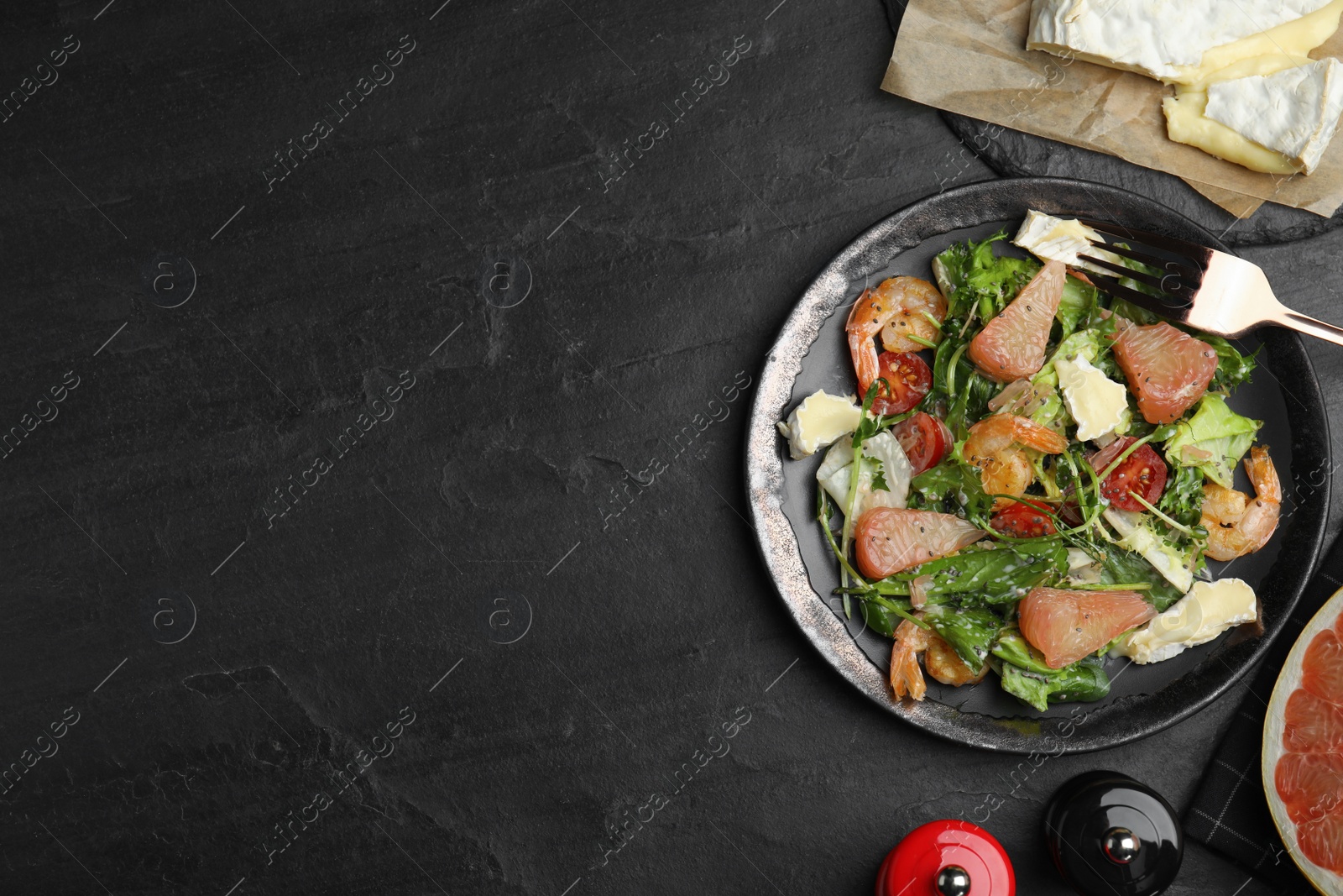 Photo of Delicious pomelo salad with shrimps served on black table, flat lay. Space for text