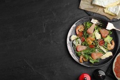 Photo of Delicious pomelo salad with shrimps served on black table, flat lay. Space for text