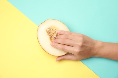 Photo of Young woman touching half of melon on color background, top view. Sex concept