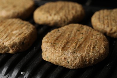 Delicious vegan cutlets cooking on electric grill, closeup