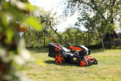 Photo of Modern lawn mower on green grass in garden