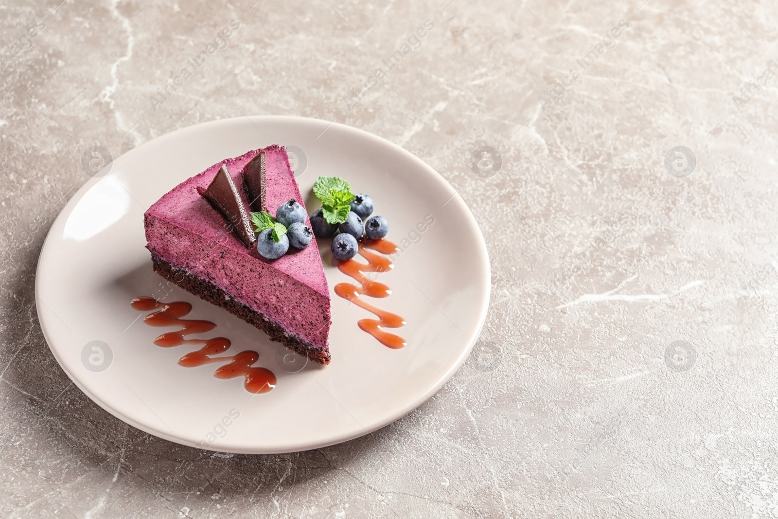 Photo of Plate with piece of tasty blueberry cake on gray table. Space for text