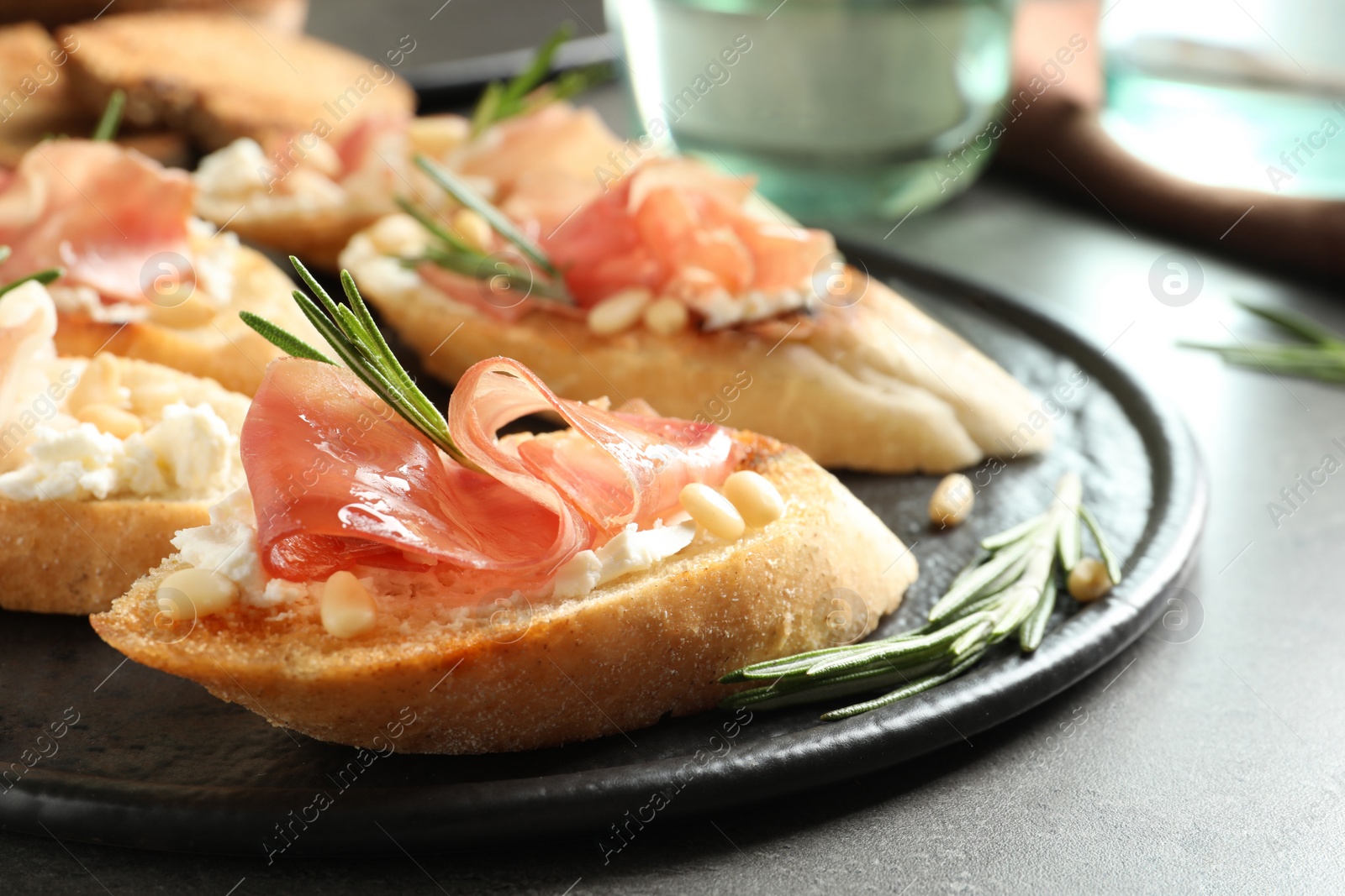 Photo of Tasty bruschettas with prosciutto and cream cheese served on table, closeup. Space for text