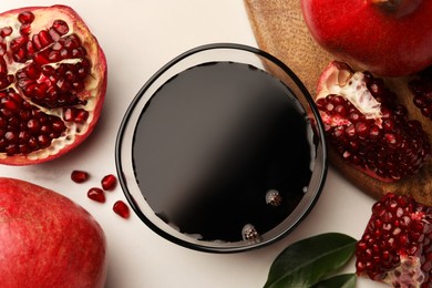 Photo of Glass bowl of tasty pomegranate sauce and fresh ripe fruits on white marble table, flat lay