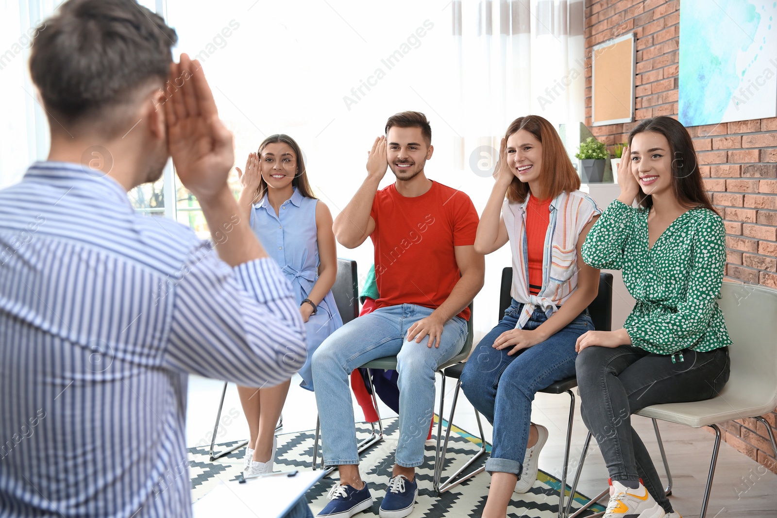 Photo of Group of young people learning sign language with teacher indoors