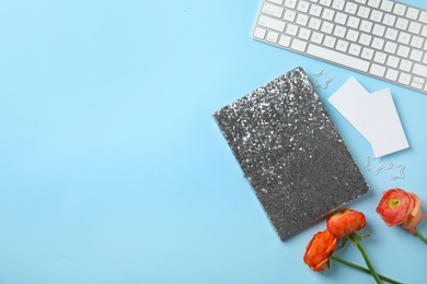 Photo of Flat lay composition with glittering notebook, keyboard and spring flowers on color background. Space for text