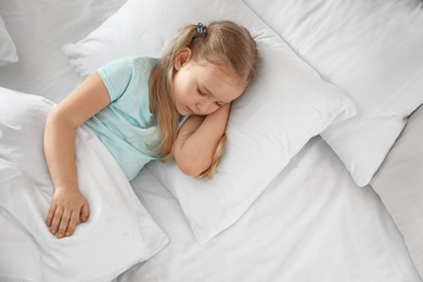 Photo of Portrait of cute little girl sleeping in large bed, above view