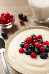 Photo of Delicious semolina pudding with berries in bowl on table, closeup