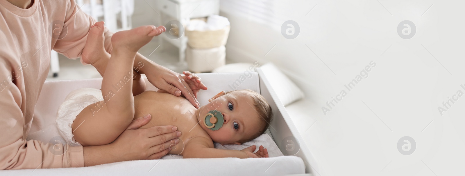 Image of Mother applying dusting powder on her cute baby at home. Banner design