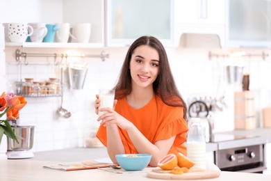 Photo of Beautiful young woman drinking milk in kitchen