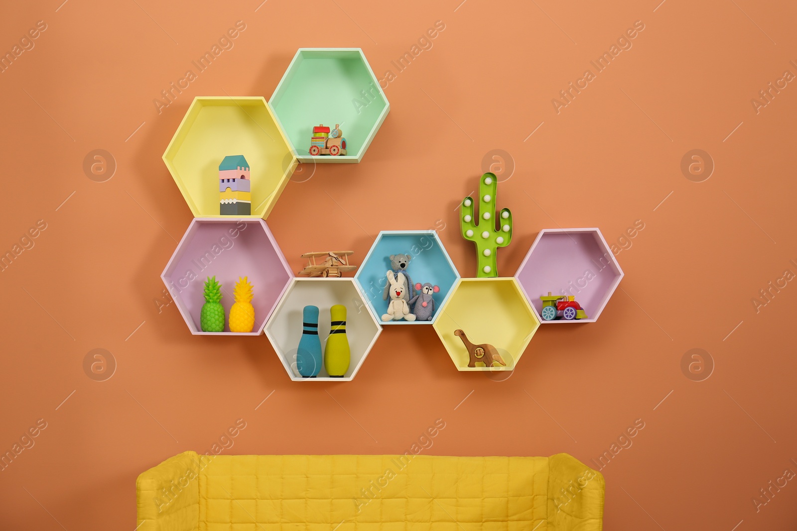 Photo of Sofa near orange wall with hexagon shaped shelves in room. Interior design