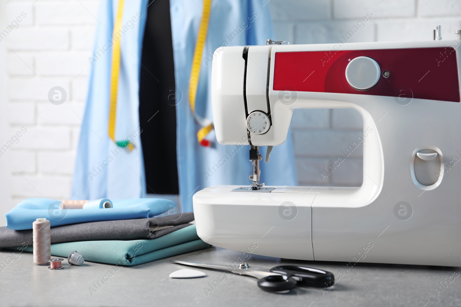 Photo of Sewing machine, fabrics and accessories for tailoring on table