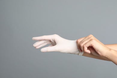 Photo of Doctor wearing medical gloves on grey background, closeup