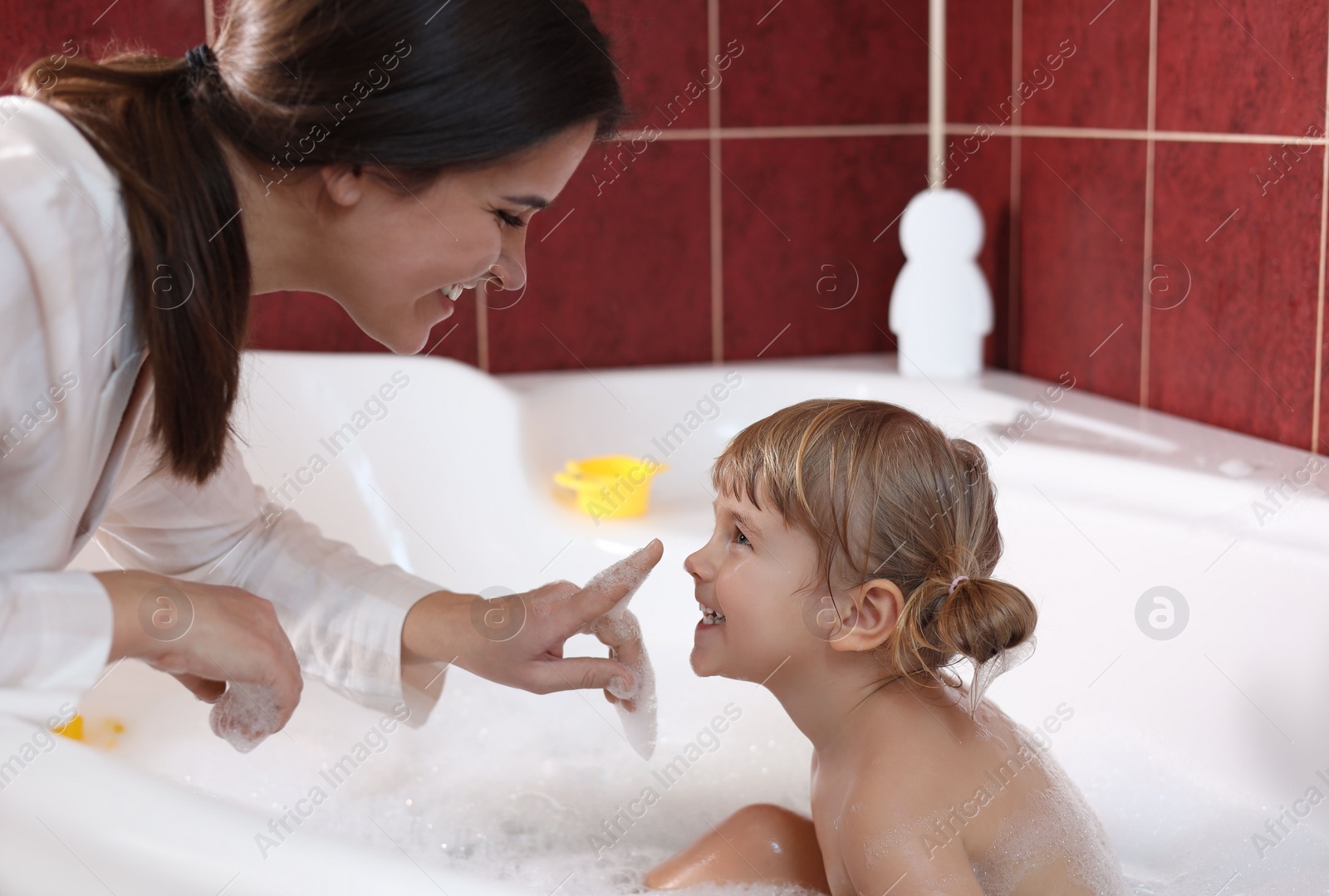 Photo of Happy mother with her little daughter spending time together in bathroom