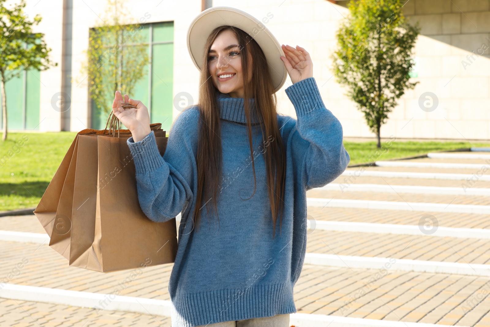 Photo of Beautiful young woman with shopping bags on city street