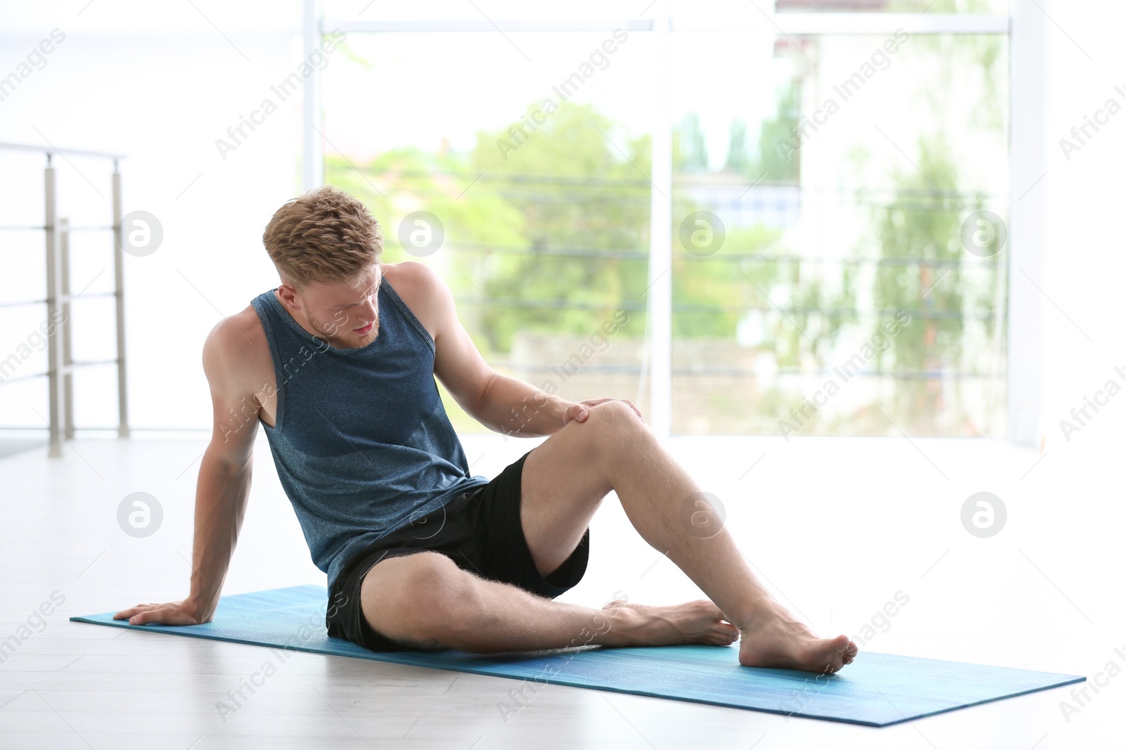 Photo of Man in sportswear suffering from knee pain at gym