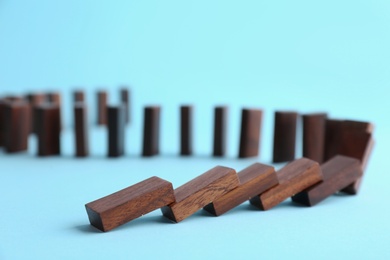 Photo of Falling wooden domino tiles on light blue background