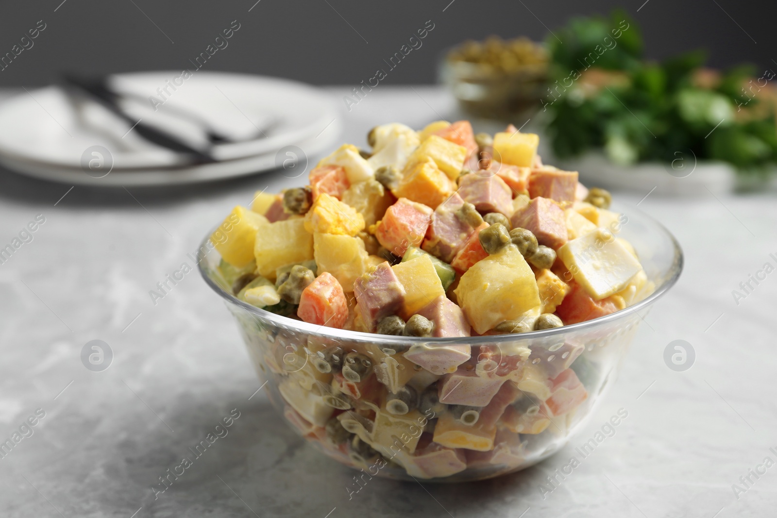Photo of Delicious russian salad Olivier served on light grey marble table