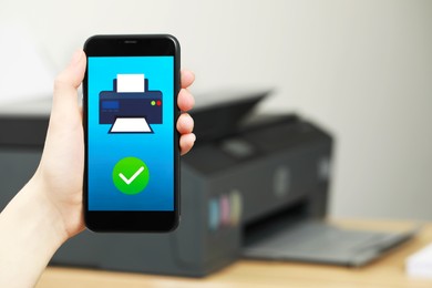Photo of Woman using printer management application on smartphone indoors, closeup and space for text. Image on device screen.