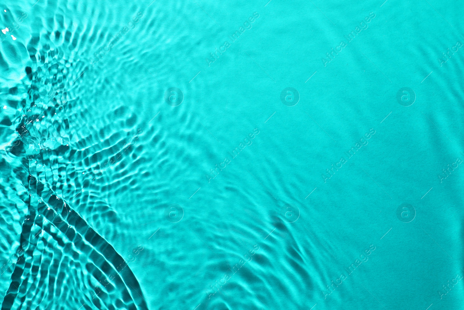 Image of Rippled surface of clear water on light blue background, closeup