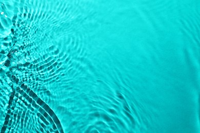 Rippled surface of clear water on light blue background, closeup