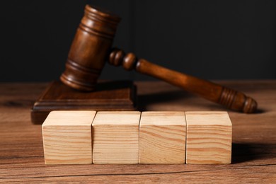 Photo of Law. Blank wooden cubes and gavel on table, closeup