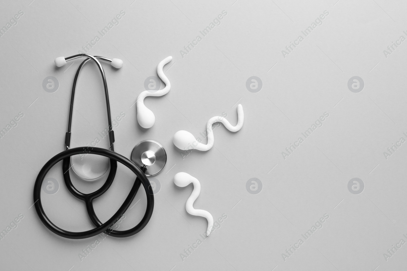 Photo of Reproductive medicine. Figures of sperm cells and stethoscope on gray background, flat lay with space for text