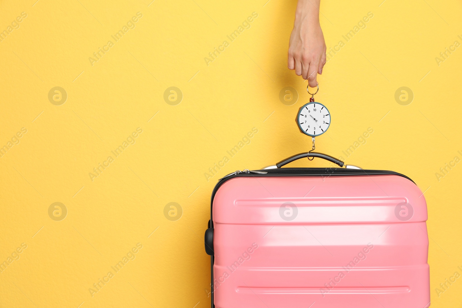 Photo of Woman weighing suitcase against color background, closeup. Space for text