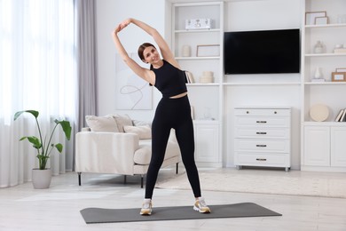 Morning routine. Happy woman doing stretching exercise at home