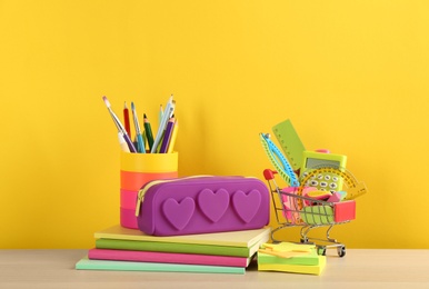 Photo of Different school stationery on table against yellow background. Back to school