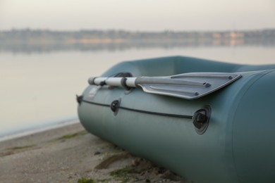 Photo of Inflatable rubber fishing boat on sandy beach near river, closeup