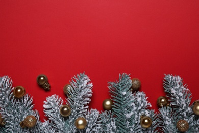 Photo of Christmas tree branches with golden baubles on red background, flat lay. Space for text