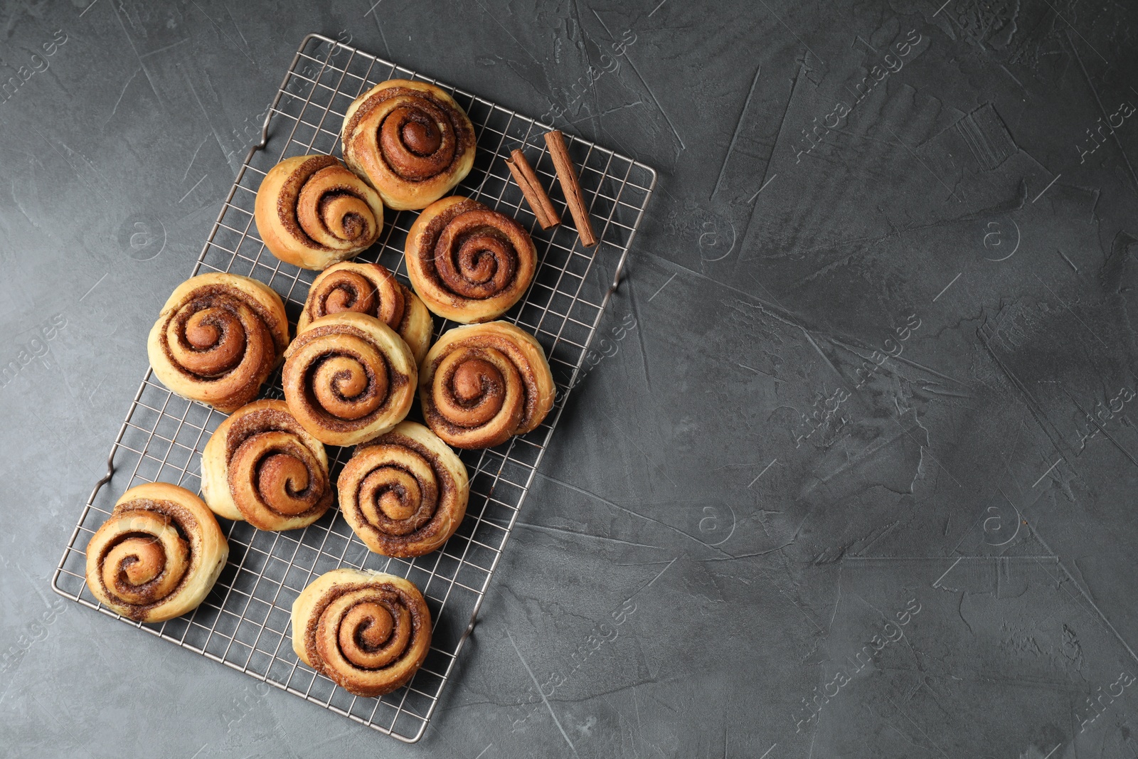 Photo of Tasty cinnamon rolls on black table, top view. Space for text