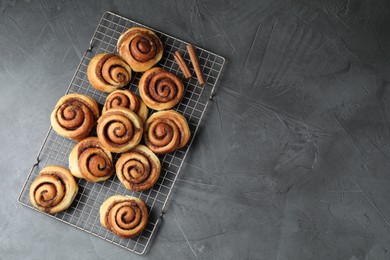 Tasty cinnamon rolls on black table, top view. Space for text