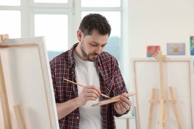 Photo of Handsome man painting in studio. Creative hobby