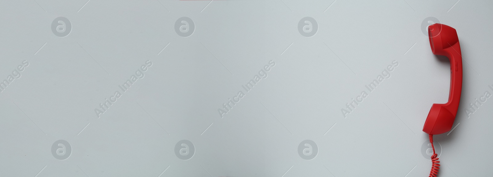 Image of Hotline service. Red telephone receiver and space for text on light grey background, top view