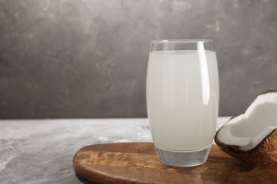 Glass of coconut water and nut on grey table. Space for text