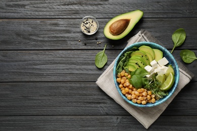 Delicious avocado salad with chickpea on black wooden table, flat lay. Space for text