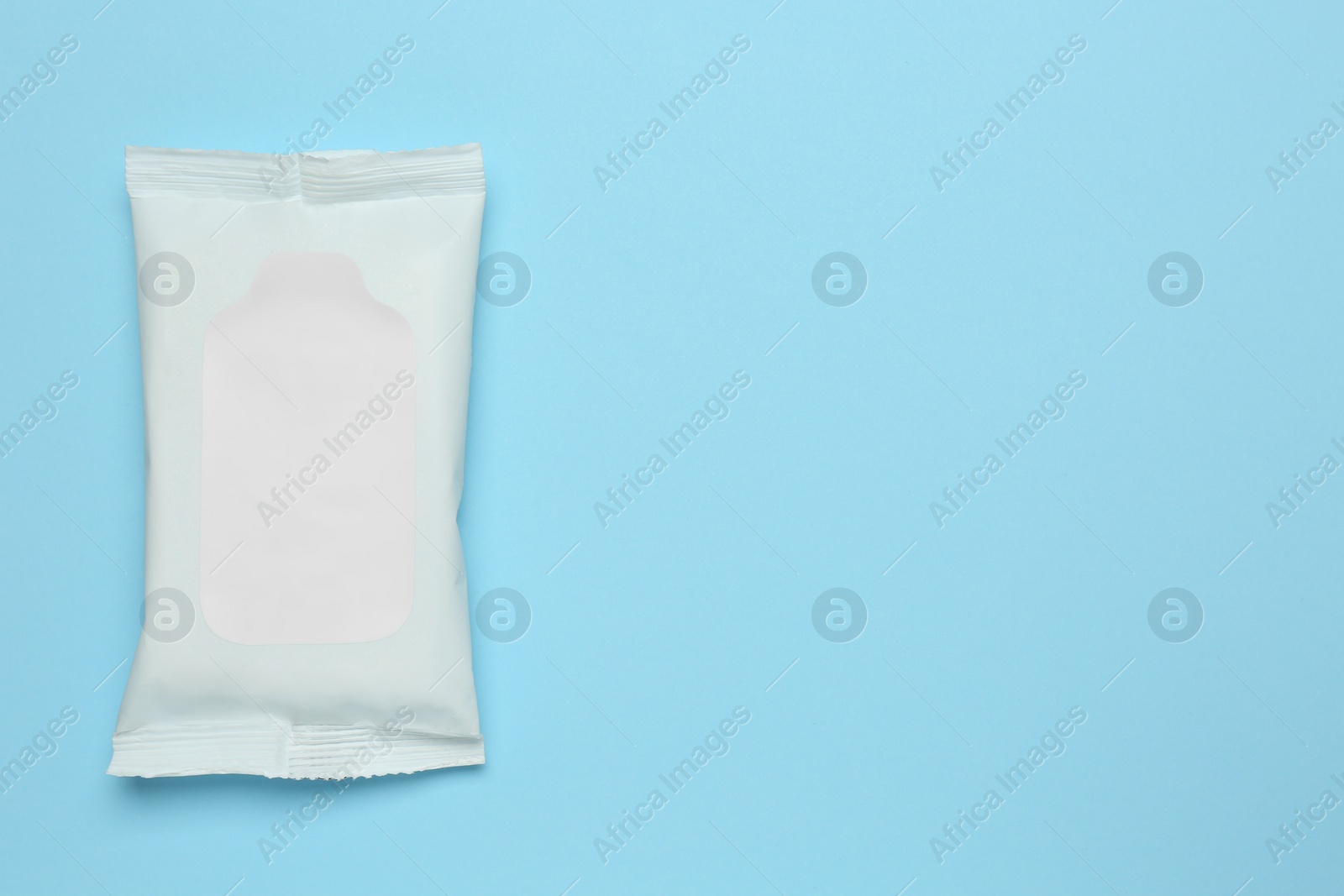 Photo of Wet wipes flow pack on light blue background, top view. Space for text