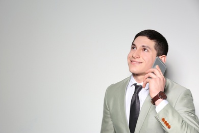 Photo of Portrait of young businessman talking on phone against light background. Space for text