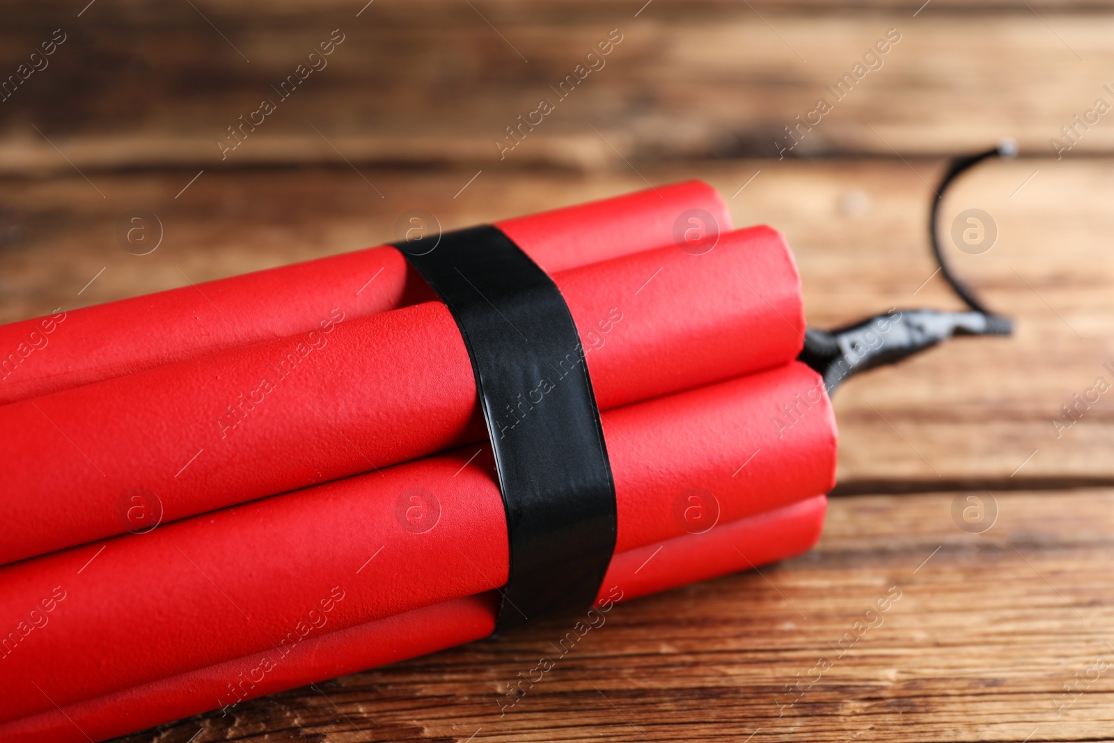 Photo of Red explosive dynamite bomb on wooden background, closeup