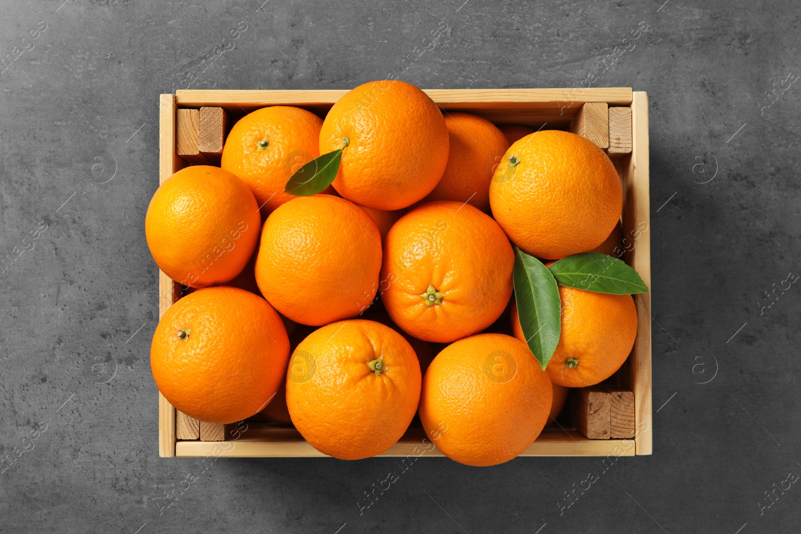 Photo of Wooden crate with ripe oranges on grey background, top view