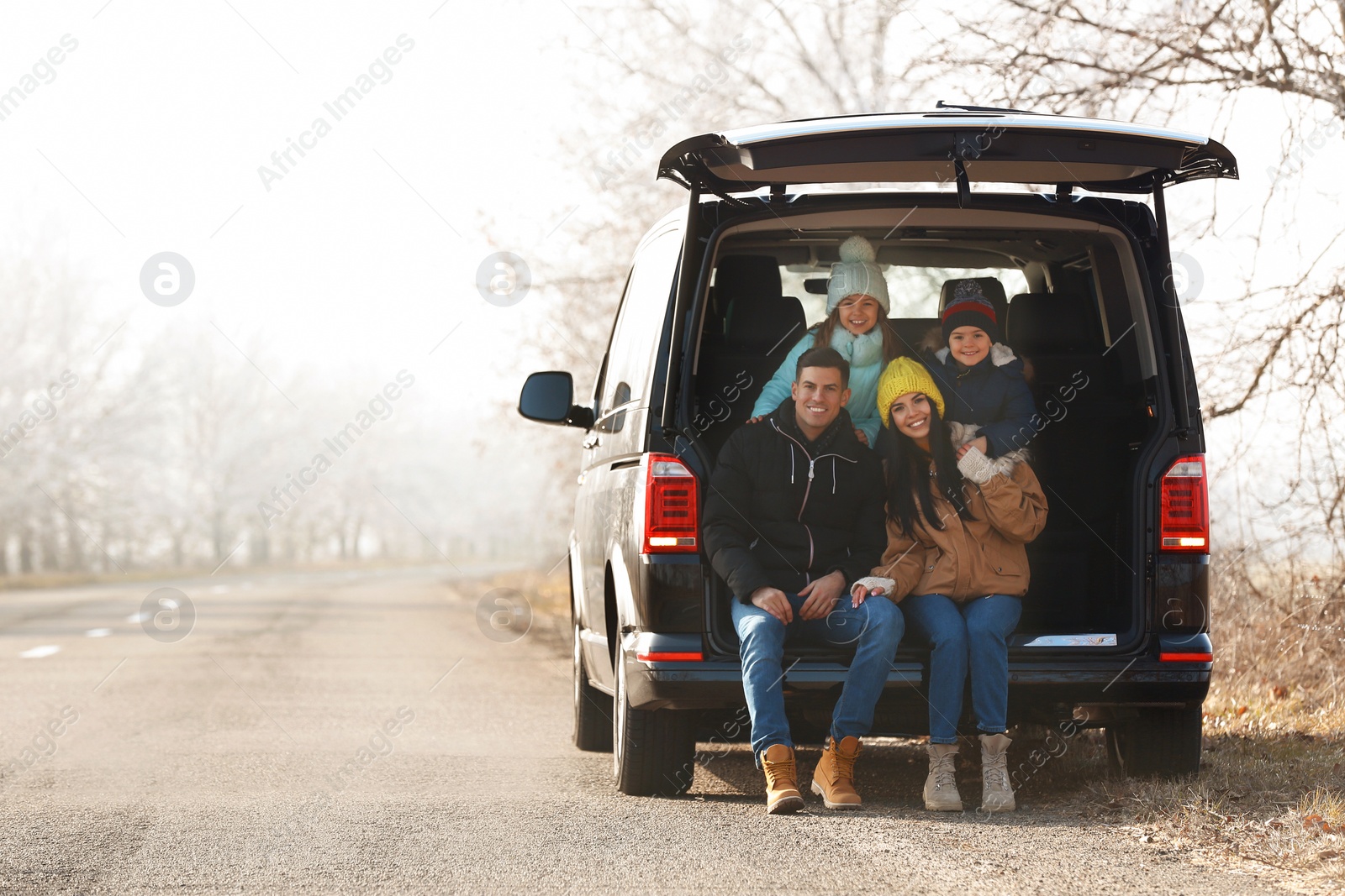 Photo of Happy family with little children in modern car trunk on road
