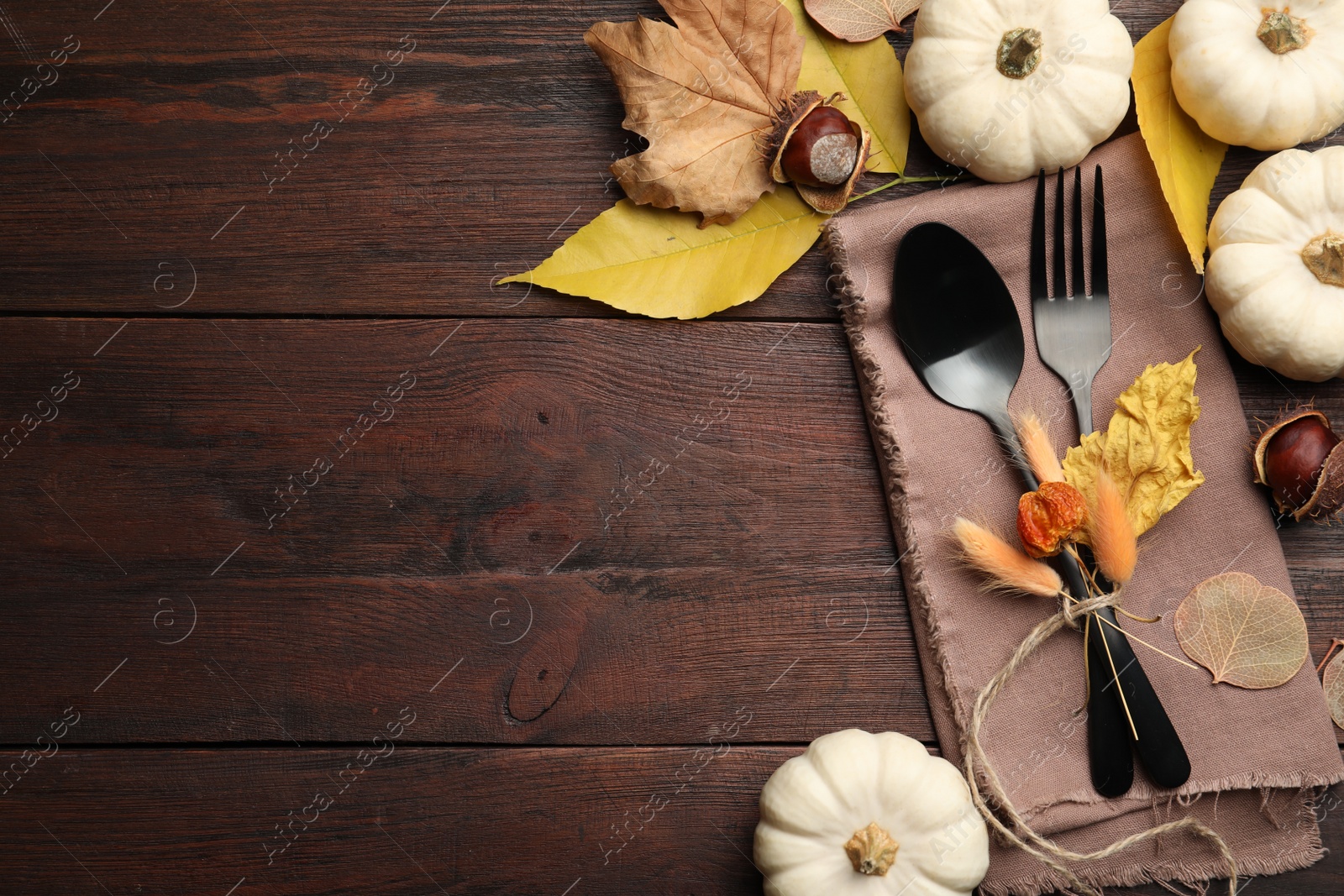 Photo of Seasonal table setting, space for text. Cutlery with pumpkins and autumn leaves on wooden background, flat lay